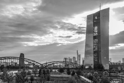 Bridge in city against cloudy sky