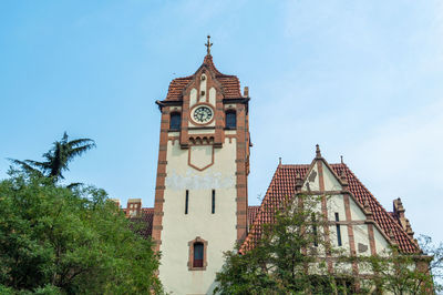 Low angle view of clock tower amidst buildings against sky