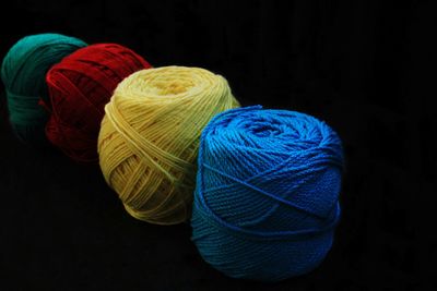Close-up of multi colored spools of threads against black background