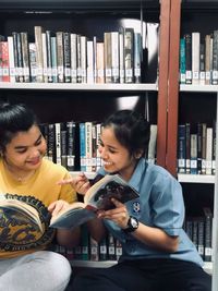 Side view of smiling young woman sitting on book