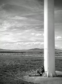 Man relaxing on field against sky