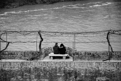 Rear view of couple sitting at riverbank