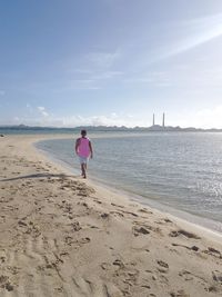 Rear view of woman on beach against sky