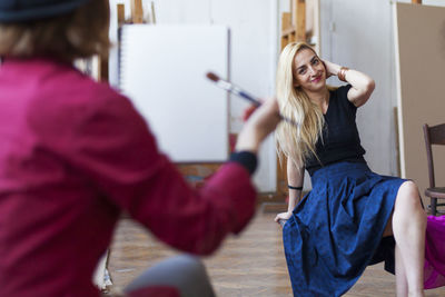 Smiling woman sitting indoors while getting painted at art studio