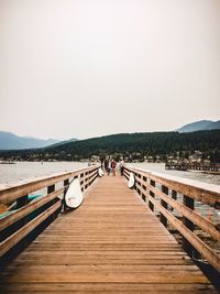 Footbridge over pier against clear sky