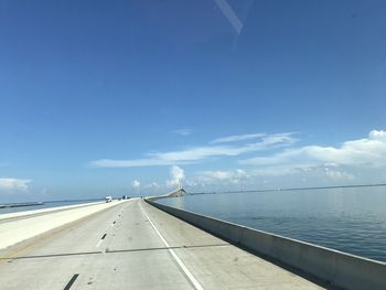 Road by sea against blue sky