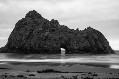 Rock formation on beach against sky