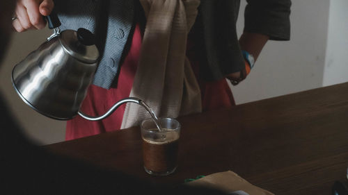 Midsection of woman pouring hot water in coffee