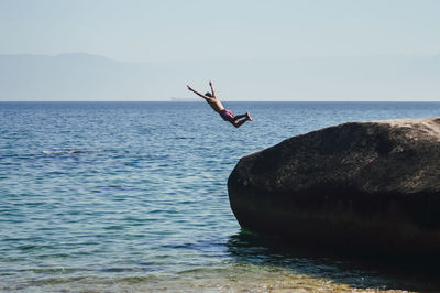 Man jumping in sea against sky