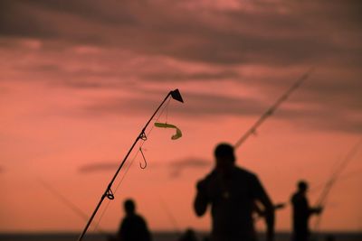 Fishing rod against orange sky during sunset