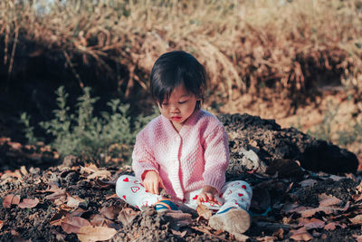 Cute baby girl looking down sitting on land