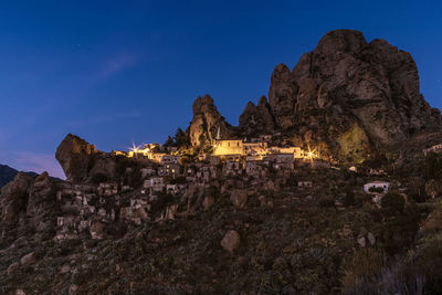 Low angle view of buildings on mountain against blue sky