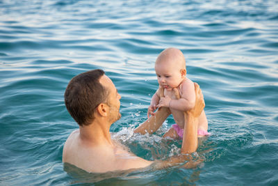 Father and daughter in sea against sky