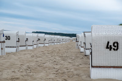 Hooded chairs on beach against sky