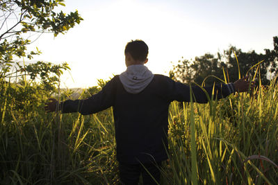 Rear view of man standing on field against sky