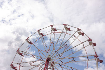 Low angle view of ferris wheel against cloudy sky