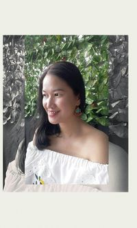 Portrait of young woman standing against plants