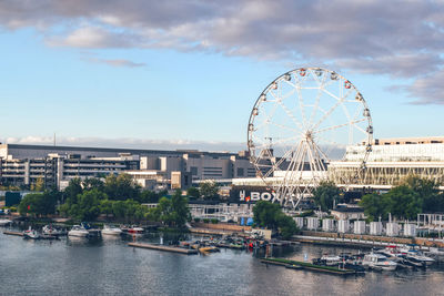 Ferris wheel in city against cloudy sky