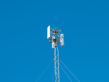 Low angle view of communications tower against blue sky