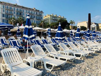 Empty chairs on beach against clear blue sky