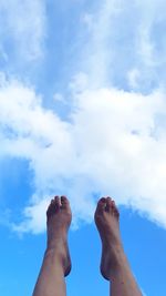 Low section of person relaxing against blue sky