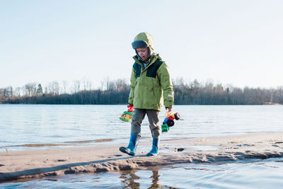 Boy playing at the beach with trucks and diggers in winter