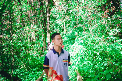 Young man standing against trees