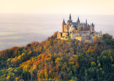 Majestic hohenzollern castle overlooking autumn forest at sunset