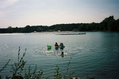 People in lake against sky