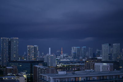 Illuminated buildings in city against sky at dusk