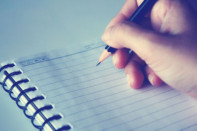 Cropped hand writing on book at table