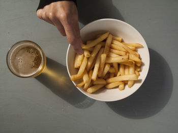 Cropped hand reaching towards french fries by beer on table