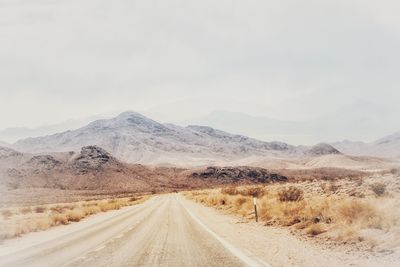 Road amidst desert against sky