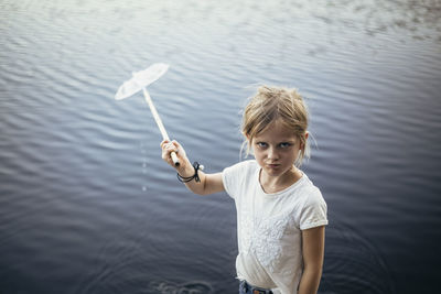 Portrait of girl with fishing net against lake
