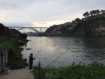 Bridge over river against cloudy sky