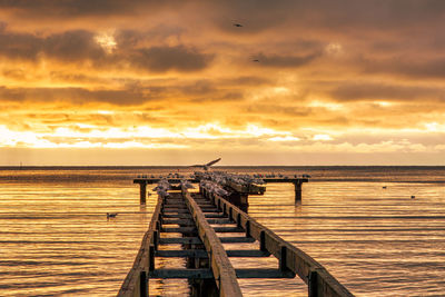 Pier over sea against sky during sunset