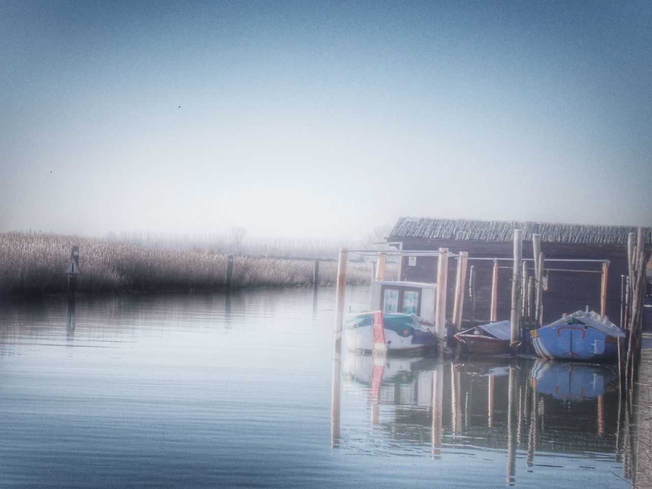 nautical vessel, water, boat, moored, mode of transport, transportation, clear sky, waterfront, built structure, copy space, lake, reflection, building exterior, architecture, river, day, nature, sky, outdoors, no people