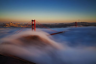 View of suspension golden gate bridge with fog  in city