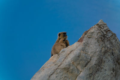 Low angle view of rock formation against clear blue sky