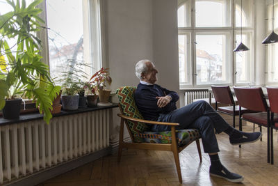Happy senior man sitting on chair at home