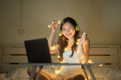 Portrait of young woman using phone while sitting on table