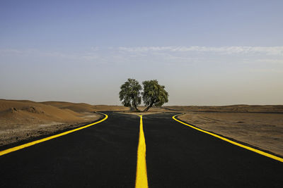 Empty road amidst landscape against sky