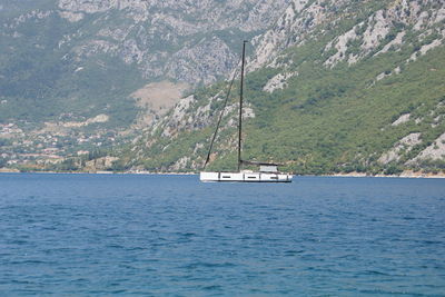 Sailboat sailing on sea against mountains
