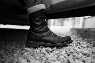 Low section of man wearing leather shoes standing on stones