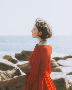 Young woman at beach against sky