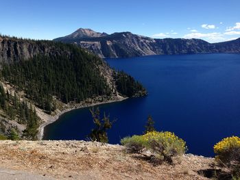 Scenic view of lake and mountains against clear blue sky