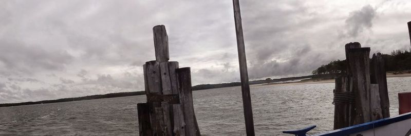 Wooden posts in sea against storm clouds