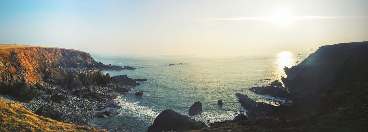 water, scenics, sea, tranquil scene, beauty in nature, rock - object, tranquility, rock formation, nature, horizon over water, sun, sky, idyllic, sunlight, sunset, cliff, rock, sunbeam, non-urban scene, reflection