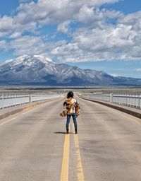 Rear view of woman on road against mountain range