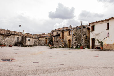 Old building by street in town against sky